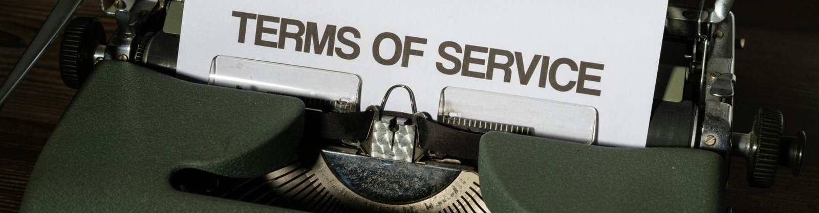 Close-up of a vintage typewriter with 'Terms of Service' paper inside, on a wooden desk.